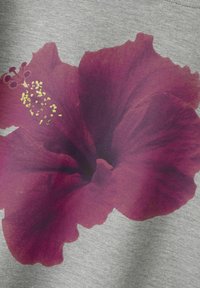 Il tessuto grigio presenta un grande design di fiori di ibisco bordeaux vividi con accenti di polline dorato, creando un forte contrasto visivo.