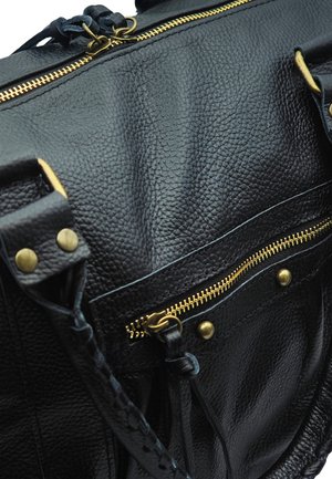 Sac en cuir texturé noir avec fermetures éclair dorées, clous en laiton et anses en cuir tressé, présenté en gros plan.