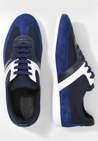 Marinblå sneakers med en kombination av mocka och mesh-material, vita detaljer på ovandelen, rund tå och platta vita gummisulor.