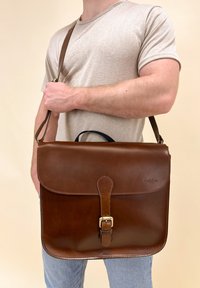 Borsa a tracolla in pelle marrone con pattina, chiusura a fibbia e tracolla. Presenta una superficie liscia e un discreto logo del marchio.
