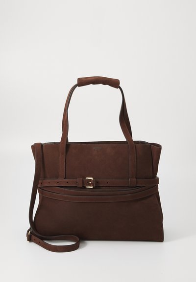 Brown suede handbag with dual handles, an adjustable strap, gold buckle detail, and a structured design. Smooth texture with minimal stitching.