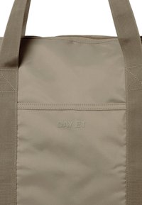 Beige Tote Bag mit dem geprägten Text "DAY ET" auf einer glatten Oberfläche und stabilen Stoffgriffen, geeignet für den Alltag.