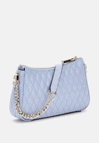 Sac à main matelassé bleu clair avec une anse en chaîne argentée, fermeture éclair et surface texturée. Design compact avec une forme triangulaire.