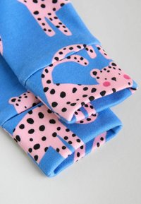 Nattøjstop med blå baggrund, der har pink leopardmønstre og sorte pletter. Bomuldsstof med rullede ærmer og manchetter.