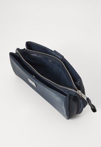 Geantă din piele de culoare bleumarin, cu o textură netedă, închidere cu două fermoare și accesorii din metal argintiu. Dispune de două compartimente interioare pentru organizare.