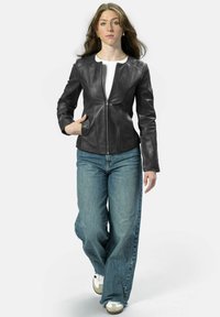 Schwarze Lederjacke mit taillierter Passform, Reißverschluss vorne und langen Ärmeln. Kombiniert mit weit geschnittenen blauen Denim-Jeans und weißen Sneakers.