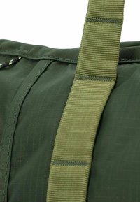 Borsa in nylon verde con superficie texturizzata, cuciture rinforzate e una tracolla larga e piatta per un comfort durante il trasporto.