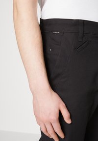Zwarte stretchbroek met een slim fit, voorzien van zijzakken, een verborgen muntzakje en een G-Star label op de tailleband.