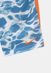 Shorts de sport à motif graphique bleu et blanc en tissu léger, avec un swoosh orange de Nike et des bordures oranges contrastantes.