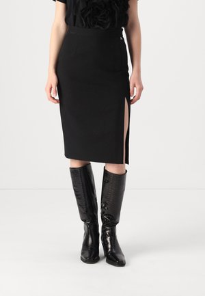 Black knee-length skirt with a side slit, made from smooth fabric. Worn with knee-high black textured leather boots. No visible fasteners.