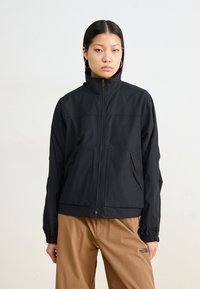 Svarte zip-up-jakke med høy krage, to frontlommer og elastiske mansjetter. Lett stoff med en jevn tekstur og subtil merkevare.
