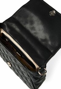 Sac à main matelassé noir en cuir texturé avec une fermeture à pression, des ferrures argentées et une doublure intérieure à motifs.