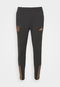 Svarta sportbyxor i slätt tyg, med orange adidas-logga, tysk landslags-emblem och tre orange ränder på sidorna.