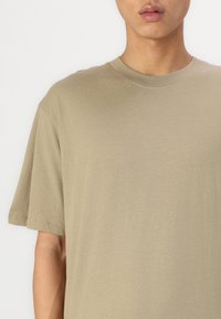Olive green short-sleeve t-shirt made of soft fabric, featuring a round neckline and a relaxed fit, with minimal stitching details.