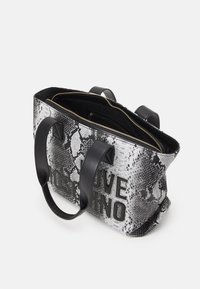 Borsa tote in bianco e nero con motivo rettile, caratterizzata dal logo "LOVE MOSCHINO", doppio manico nero, chiusura con zip e tessuto testurizzato.