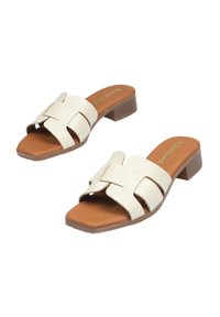 Sandalias deslizantes blancas con tiras cruzadas y un acabado texturizado, plantillas marrones y un tacón bajo. Diseño casual adecuado para el clima cálido.