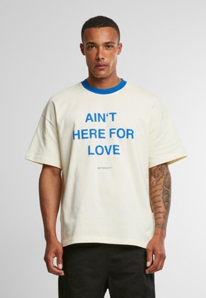 Cream short-sleeve t-shirt with a blue collar and bold blue text reading "AIN'T HERE FOR LOVE" on the front. Midweight cotton fabric.