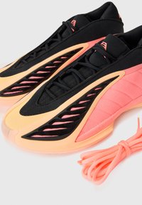 Atletické boty s černým síťovaným svrškem, růžovými akcenty a elegantním designem. Oranžová gumová podešev má boční výřezy. Obsahuje růžové tkaničky.