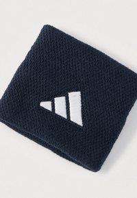 Tmavomodrý texturovaný látkový náramok s bielym vyšívaným trojuholníkovým logom, na ktorom sú tri stúpajúce pruhy. Kompaktný a obdĺžnikový tvar.