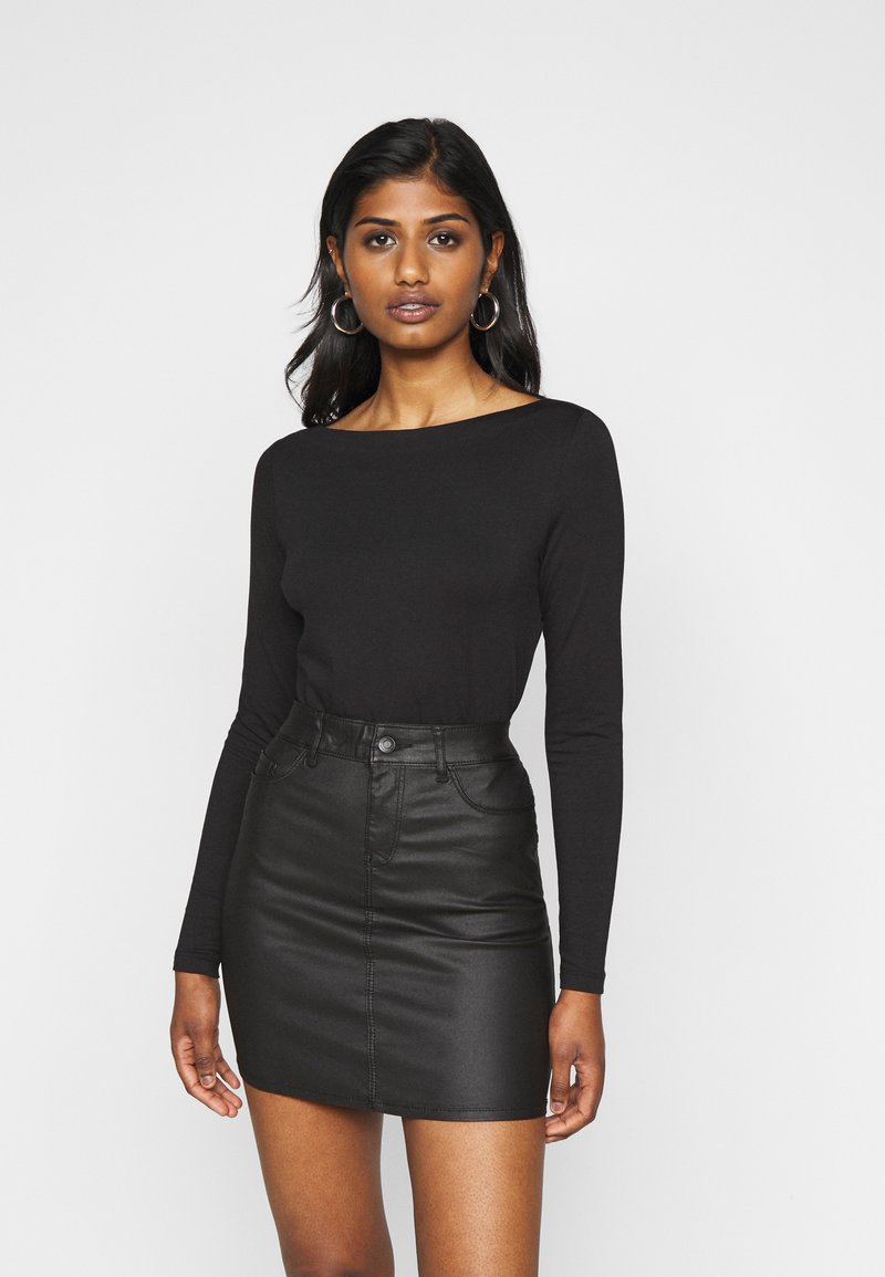 Black long-sleeve top with a wide neckline paired with a black leather mini skirt featuring front pockets and a button closure.