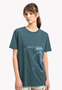 Teal katoenen T-shirt met een blauw abstract grafisch ontwerp, korte mouwen en een ronde hals, met een ontspannen pasvorm.