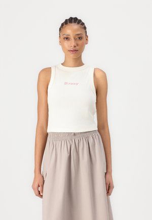 Débardeur blanc à côtes avec un logo "roxy" rose, associé à une jupe midi fluide de couleur brun clair avec une taille élastique.