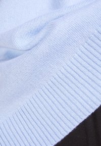 Ljust blått stickat tyg med en mjuk textur, med en ribbad kant i en mörkare nyans, som visar en mjuk och mysig framtoning.