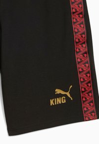 Fekete rövidnadrág, piros mintás oldalsávval, arany "KING" felirattal és arany Puma logóval, sima anyagból készült.