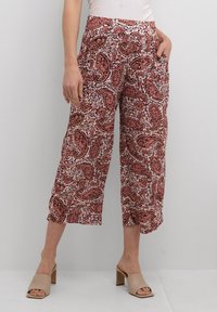 Pantalons courts à motif paisley rouge et blanc, avec une coupe décontractée, présentant des poches latérales et un tissu léger.