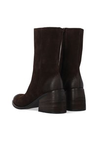 Hnědé semišové kotníkové boty s mírně zakřiveným šaftem, zaoblenou špičkou a texturovaným dřevěným blokovým podpatkem. Mají hladkou koženou akcentaci.