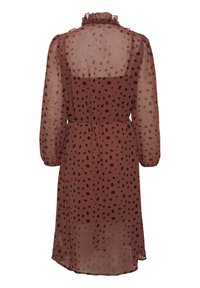 Brązowa sukienka w kropki ma transparentny materiał z czarnymi kropkami, falbaniaste wykończenie dekoltu, długie rękawy oraz dopasowaną talię.