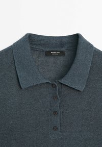 Polo en maille gris foncé avec quatre boutons noirs et un col pointu, étiqueté Massimo Dutti, fabriqué en Chine.
