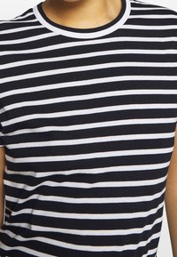 Czarny i biały T-shirt w paski z okrągłym dekoltem, krótkimi rękawami i miękką, gładką fakturą. Paski są równomiernie rozmieszczone i jednolite.