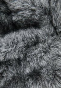 Umjetna krzna tkanina s mješavinom crnih i sivoj tonova, koja se odlikuje mekim, pahuljastim teksturom i nepravilnim, prirodno izgleda obrascima kroz cijelu površinu.