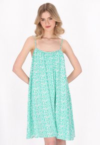 O rochie teal cu un model abstract alb, având bretele subțiri și ajustabile, cu o croială lejeră și fluidă, prezintă detalii încrețite la nivelul bustului.