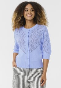 Svetlo modra pletena jopica z čipkastim vzorcem na ramenskih delih, rebrastimi manšetami in sprednjim zapiranjem na gumbe. Usklajena z črtastimi hlačami.