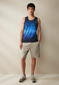 Meeste sinine ilma varrukateta tank top ombre efektiga, koos heledate hallide lühikeste pükstega ja hallide spordijalatsitega. Lihtne disain, ilma mustriteta.