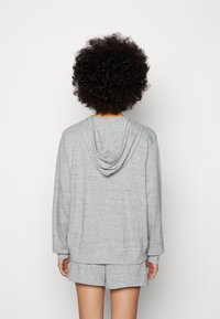 Gray hooded sweatshirt in a soft texture, featuring a relaxed fit, long sleeves, and a drawstring hood. Paired with matching shorts.