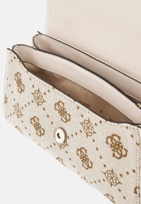 Beige stof håndtaske med guld logo mønstre, en tryklås og et lyst beige interiør, der inkluderer to rum.