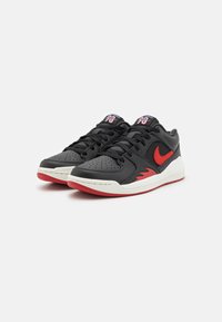 Sneakers in pelle nera con accenti rossi e punta perforata. Presentano una suola intermedia bianca e una suola esterna rossa. Sistema di allacciatura standard.