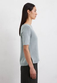 Helles blaues Kurzarm-Sweatshirt mit Rundhalsausschnitt, gerippten Kanten und seitlichen Schlitzen. Hergestellt aus einem glatten, leichten Material.