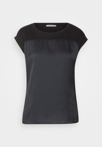 Blouse noire à manches courtes avec un panneau transparent sur le haut de la poitrine et un col rond, présentée sur un fond clair uni.