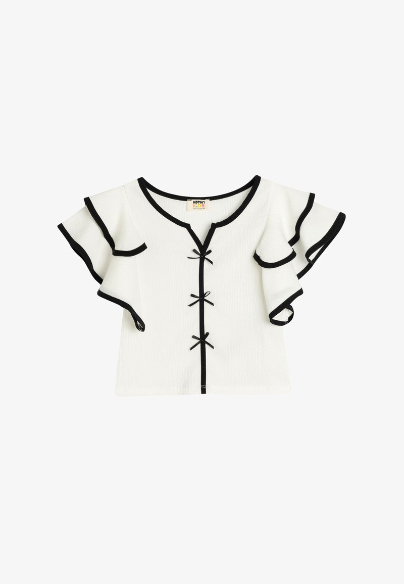 Witte top met korte mouwen en zwarte afwerking, met uitlopende ruffles en een V-hals. Bevat decoratieve strikken en een gestructureerde stof. Casual ontwerp.