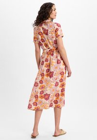 Abito midi floreale rosa, con maniche corte, vita annodata e gonna fluida decorata con vivaci motivi arancioni e viola. Tessuto dalla consistenza liscia.