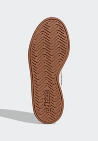 Smeđa gumena potplat obuće s uzorkom kosti ribe i logotipom „adidas“. Ima glatke rubove i teksturiranu površinu za prianjanje.