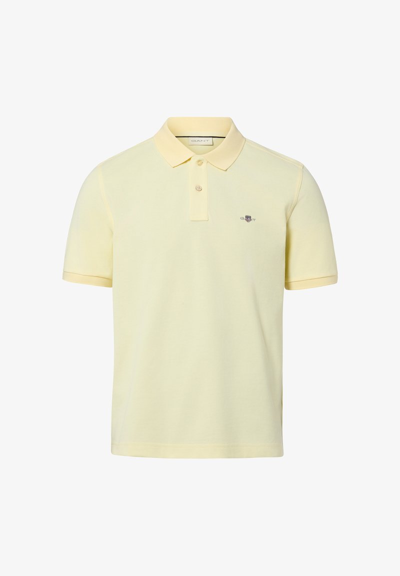 Polo à manches courtes de couleur jaune clair avec deux boutons et un petit logo brodé sur la poitrine, côté gauche.