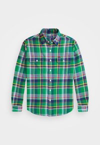 Camicia a quadri verde con dettagli viola, gialli e bianchi. Presenta due tasche sul petto e un collo con bottoni. Tessuto di cotone.