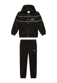 Felpa nera con zip, strisce bianche, cappuccio attaccato e tasche frontali, abbinata a pantaloni della tuta neri con coulisse e logo.