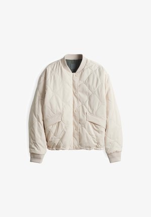 Hellbeige gesteppte Jacke mit rundem Halsausschnitt, Druckknopfverschluss und zwei großen Fronttaschen. Eingeknöpfte Ärmel und weiche Textur.