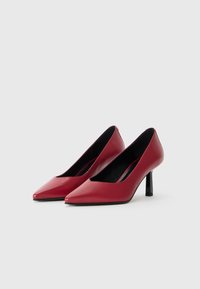 Red leather pointed-toe heels with a low-cut vamp and a slender black stiletto heel. Smooth texture with a minimalist design.